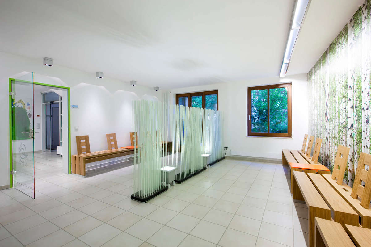 Tierarztwartezimmer mit Raumteilersystem und modernen Holzbänken.