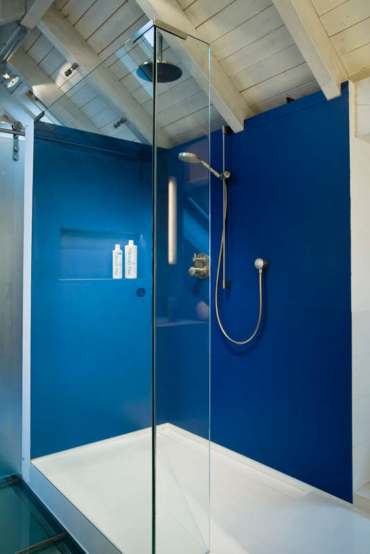 Farbakzent im Duschbereich, ausgeführt mit großformatigen fugenlos verlegten Feinsteinzeug-Fliesen.