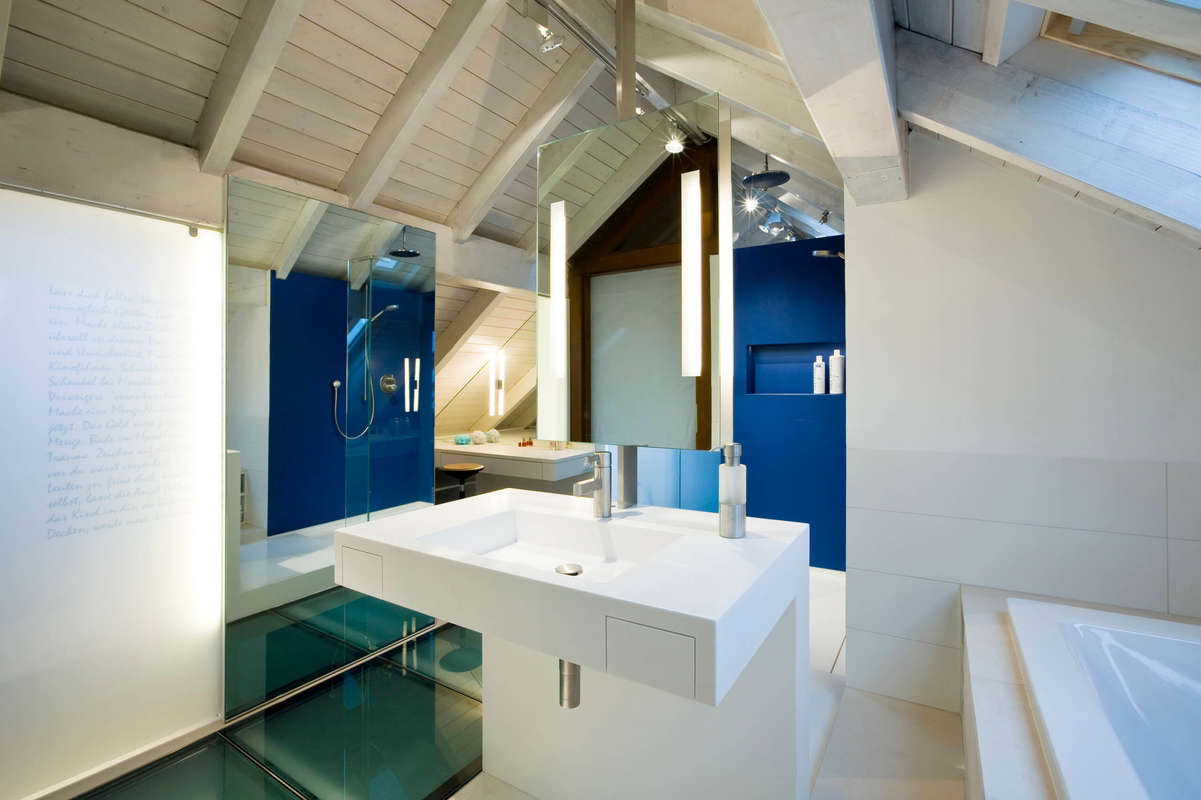 Badezimmer mit weißem Interieur aus HI-MAC. Duschbereich in blauem Feinsteinzeug.